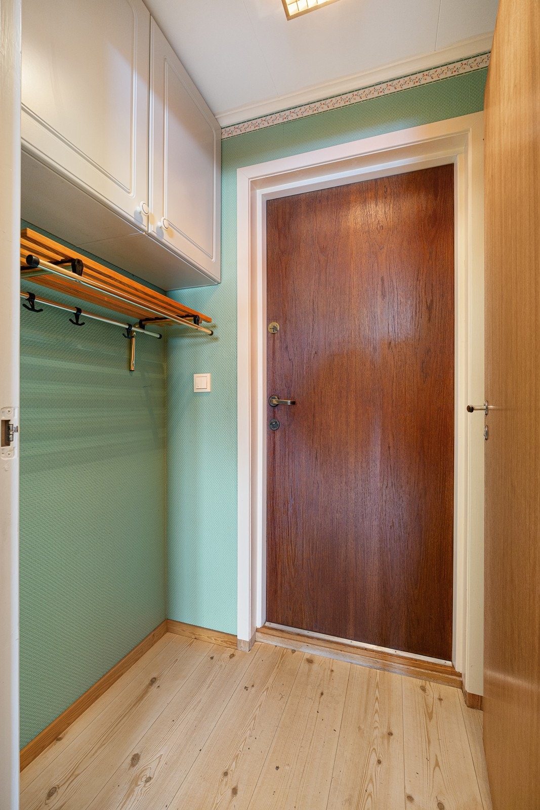 Ved bruk av inngangen i første etasje kommer man inn i et vindfang. Rommet er utstyrt med klesoppheng, hattehylle og to veggskap. Galleribilde