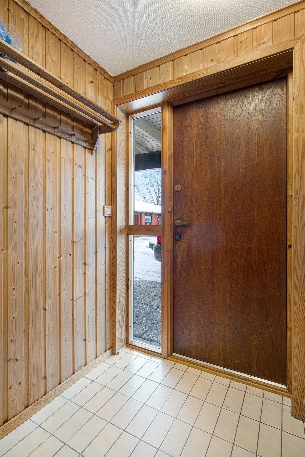 Vindfanget i underetasjen har flislagt gulv med varmekabler - og vegger med ubehandlet trepanel. Det er åpen garderobeløsning. Galleribilde