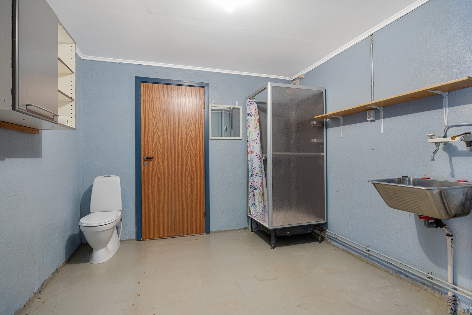 I underetasjen finnes også dette badet som har malte overflater og er utstyrt med toalett, dusjkabinett, utslagsvask og opplegg for vaskemaskin/tørketrommel. Galleribilde