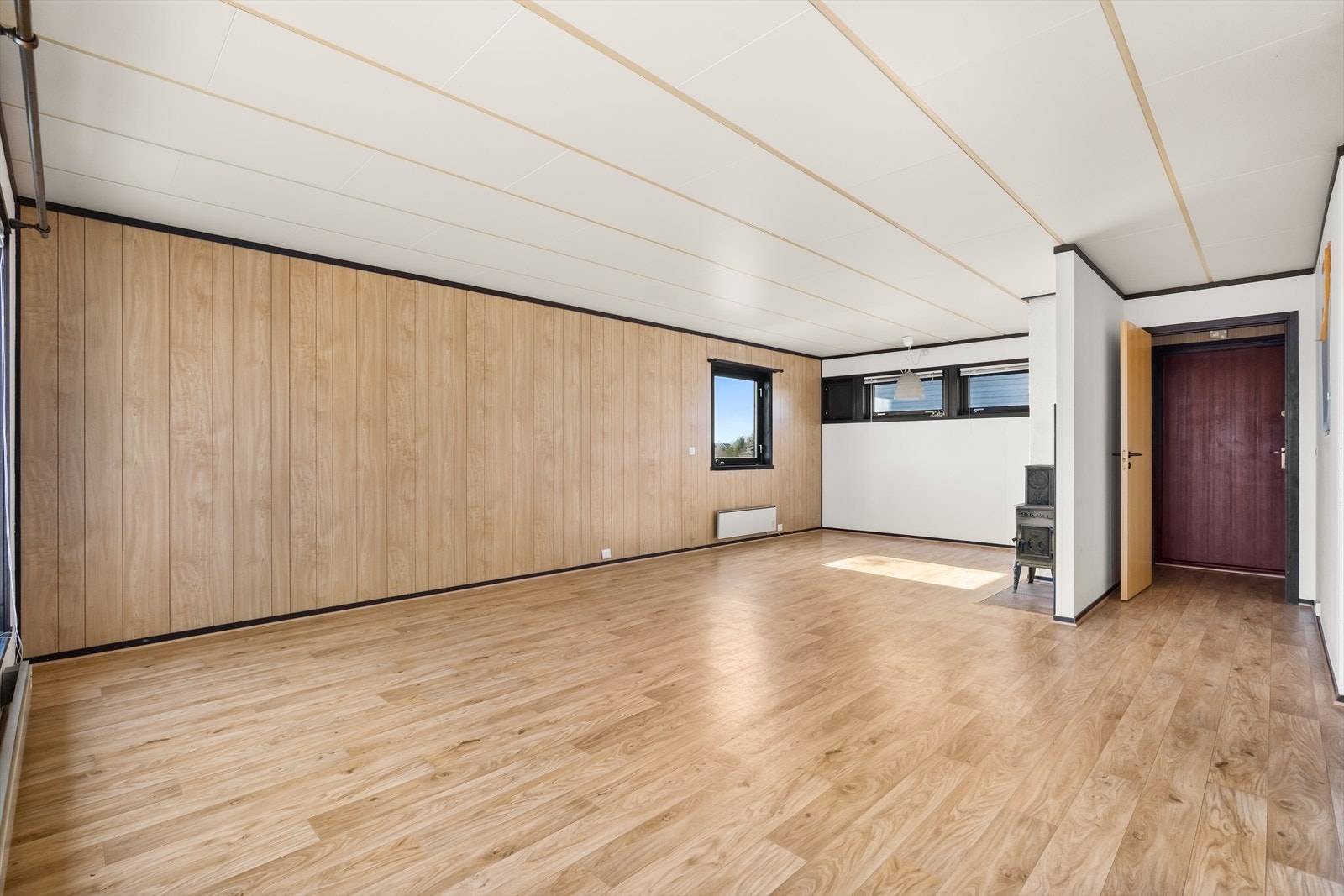 Boligen har en romslig stue med peisovn Galleribilde