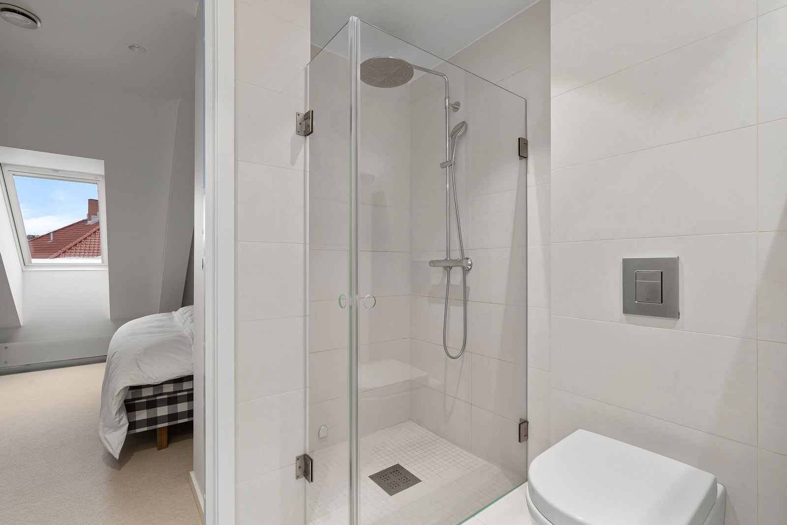 Innredet med romslig dusjnisje med innfellbare dusjvegger, regnfallsdusj og hånddusj, samt veggmontert klosett. Galleribilde