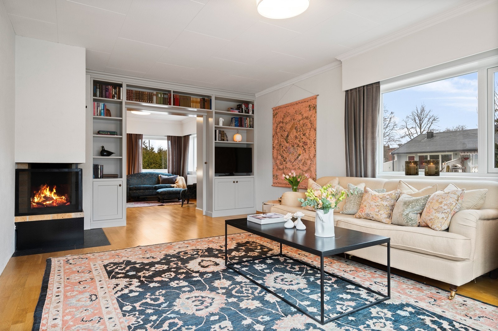 Stuen er et av boligens hovedrom, med en stemningsfull, åpen peis og plassbygde hyller. Galleribilde