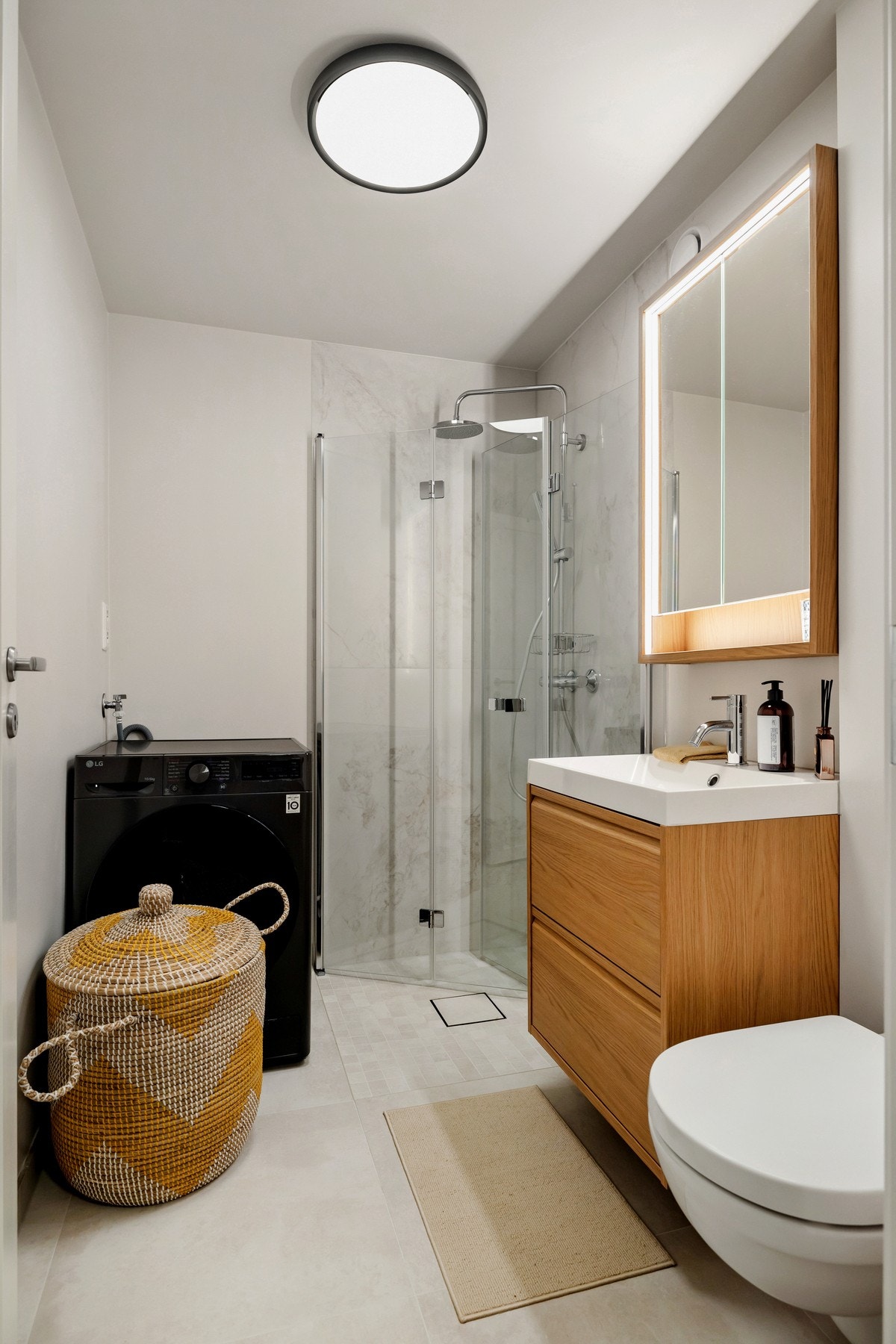 Videre har badet dusjnisje med både regnfalls- og håndholdt dusj og toalett. Servantinnredningen har to skuffefronter og det er montert speilskap med belysning. Badet har også opplegg for vaskemaskin. Galleribilde