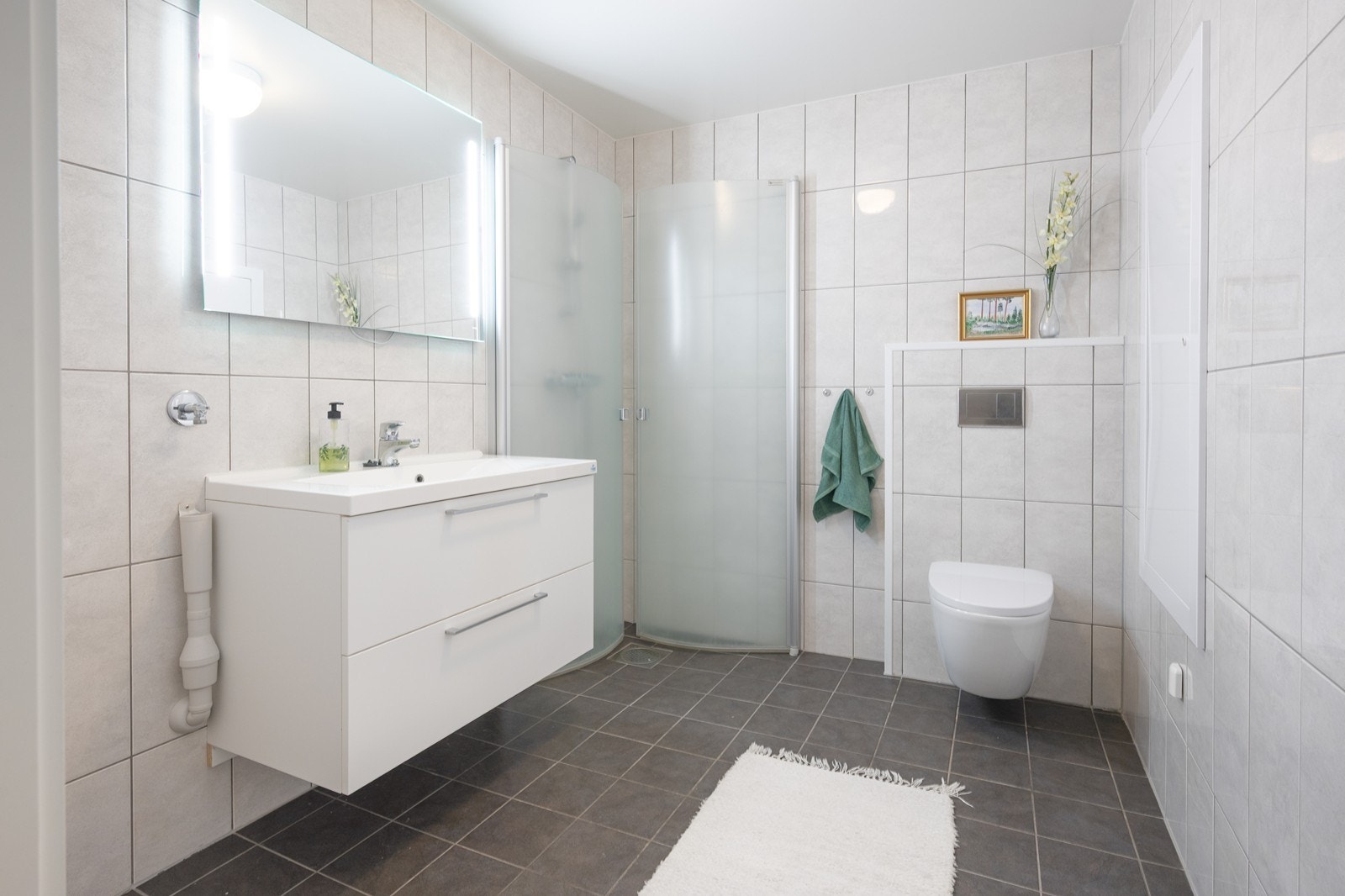 Helfliset bad/vaskerom med stilren innredning, dusjnisje og vegghengt wc Galleribilde