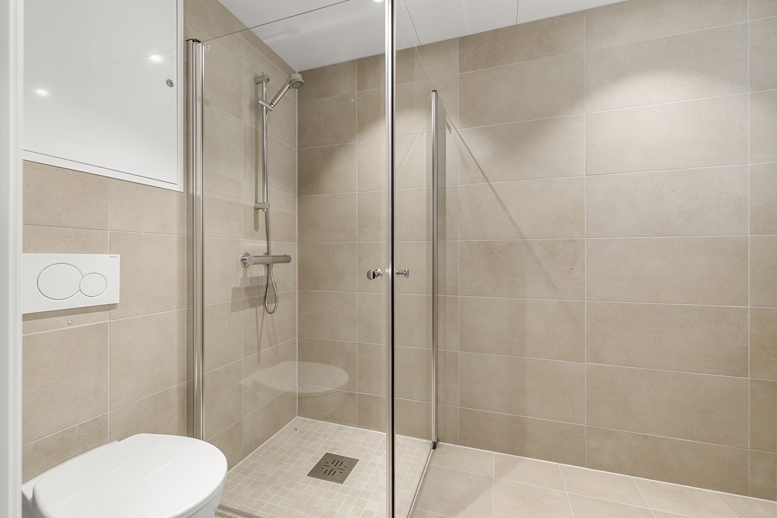 Dusjhjørne med innfellbare glassdører og vegghengt toalett for enkelt renhold. Galleribilde