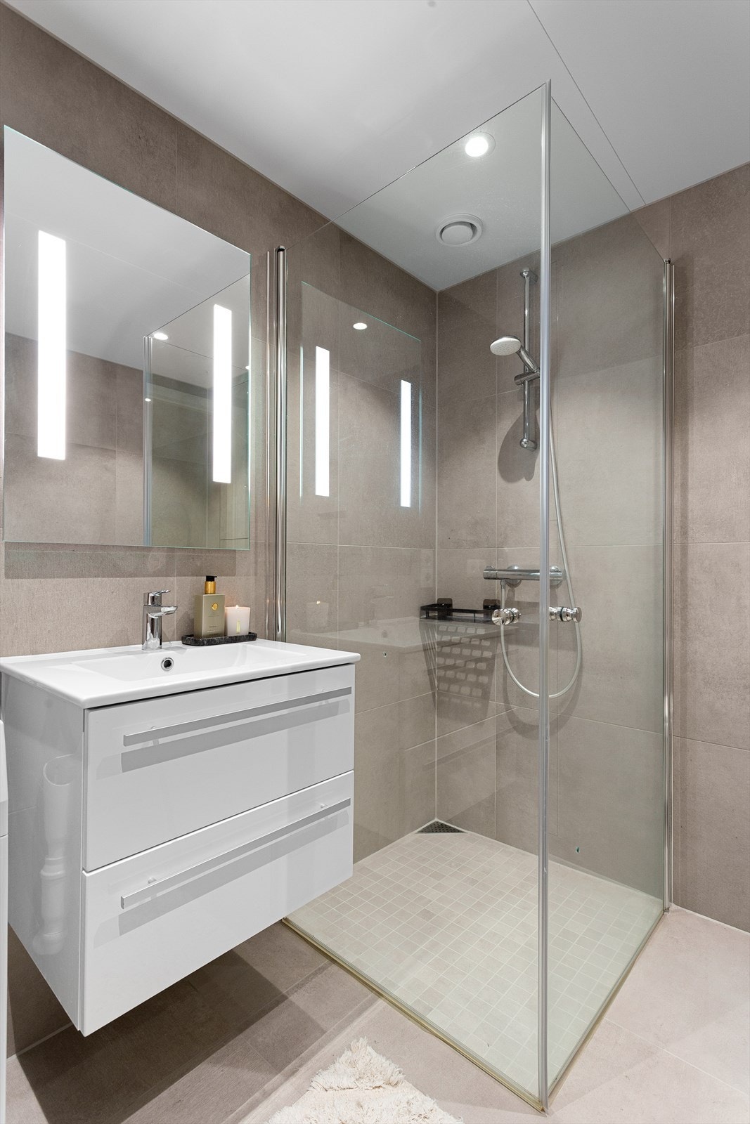 Dusjhjørne med dusjvegger i glass og vegghengt toalett. Opplegg for vaskemaskin. Vaskemaskin medfølger. Galleribilde