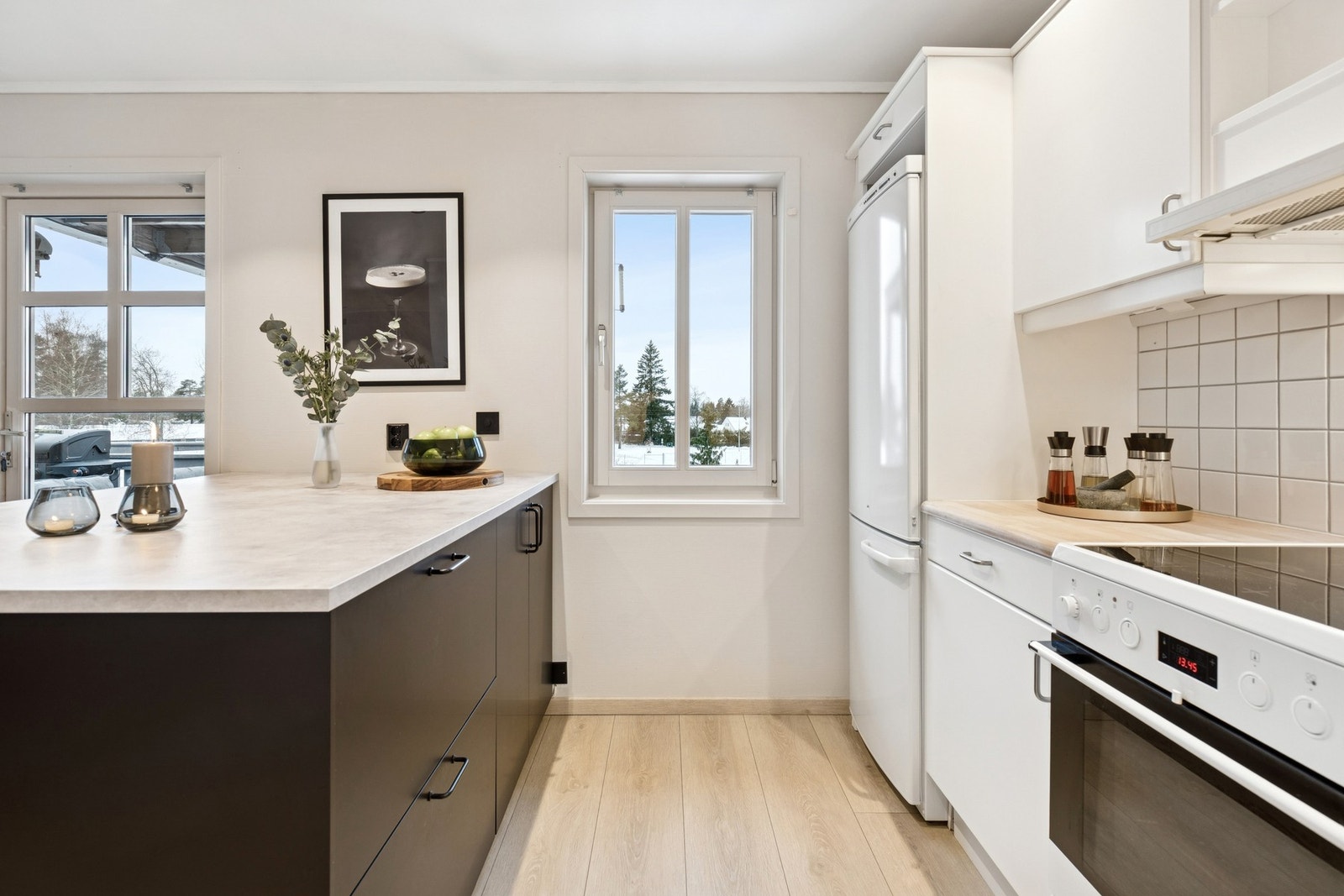 Innredning med hvite, slette fronter og benkeplater i tre gir et tidløst uttrykk, og det er flislagt mellom benk og overskap. Galleribilde