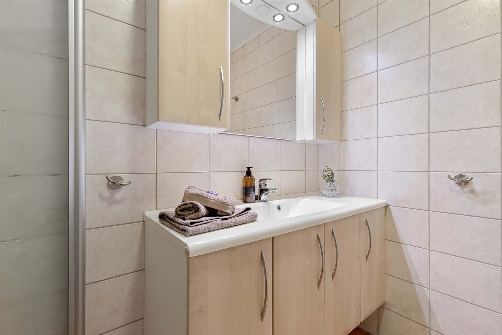 Badet er utstyrt med servantinnreiing, spegel, toalett, dusjhjørne og varmekablar i golv. Galleribilde