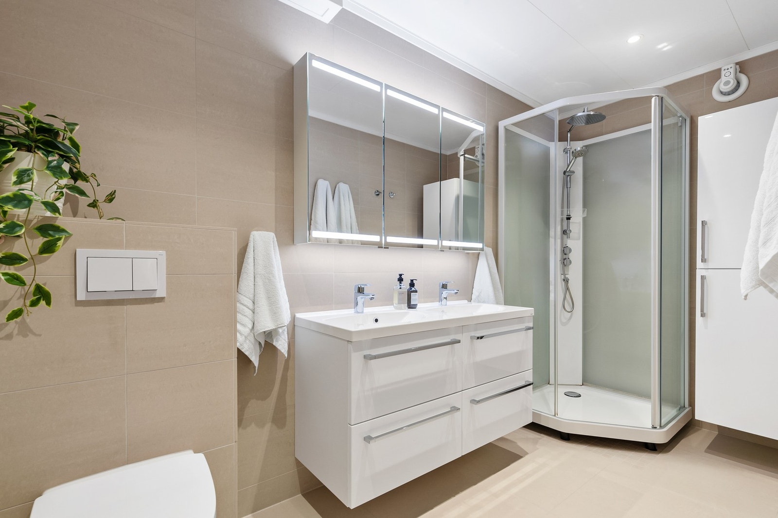 Pent bad fra 2019 med flislagte gulv- og veggflater og himling med takess og innfelte downlights Galleribilde