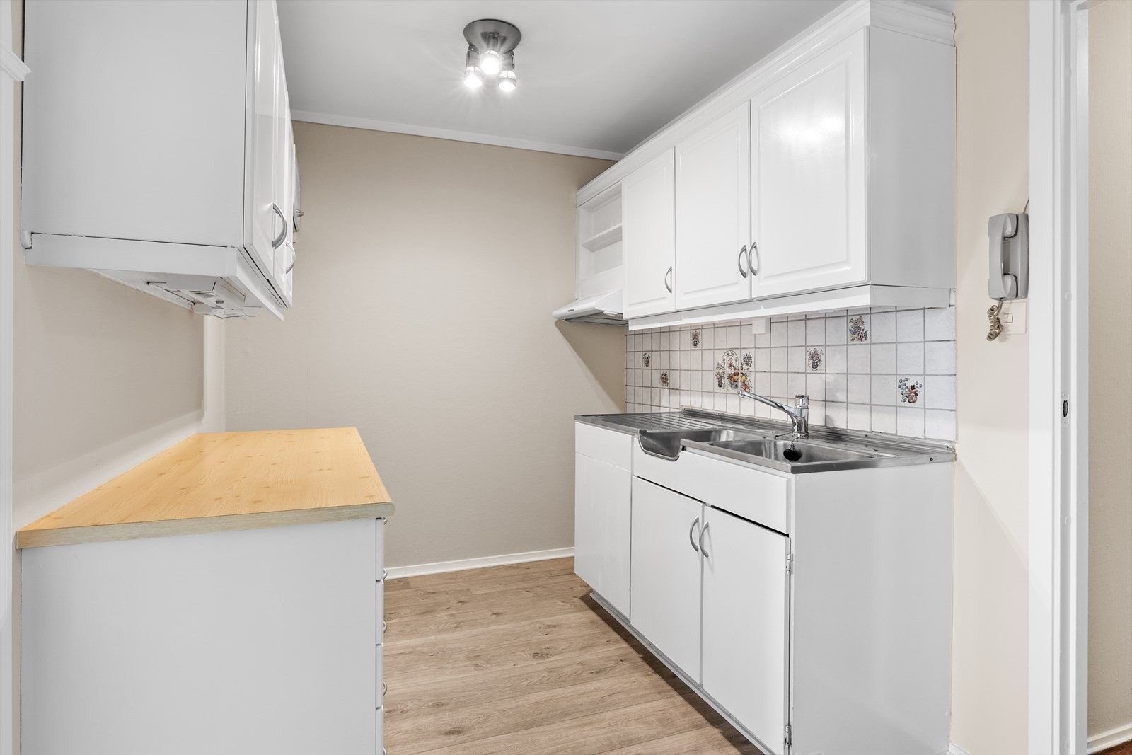 Mellom benkeplater og overskap er det flislagt, noe som både beskytter veggflatene mot fukt og søl, og samtidig tilfører rommet et praktisk og ryddig preg. Flisene gir en slitesterk overgang mellom arbeidsflate og vegg. Galleribilde