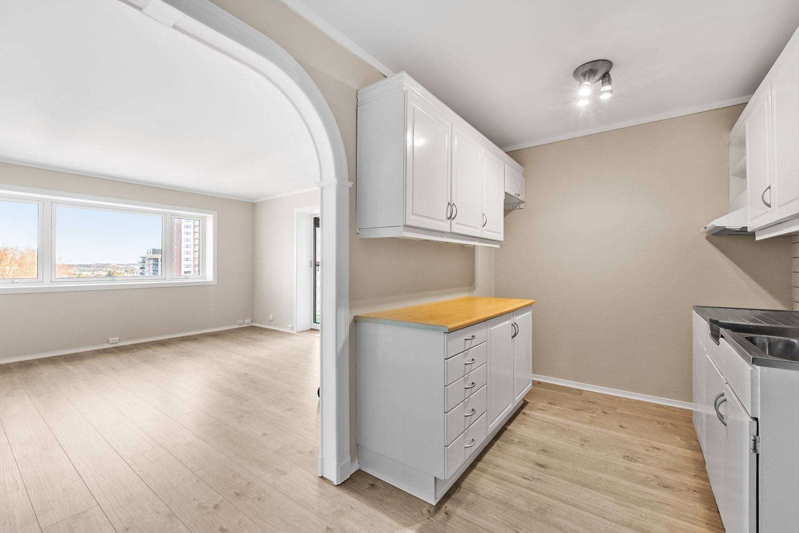 Kjøkkenet fremstår som et funksjonelt rom med en praktisk utforming. Gulvet er belagt med laminat, og veggene er utført med malte, slette flater som sammen med malt himling gir et lyst og helhetlig uttrykk. Galleribilde