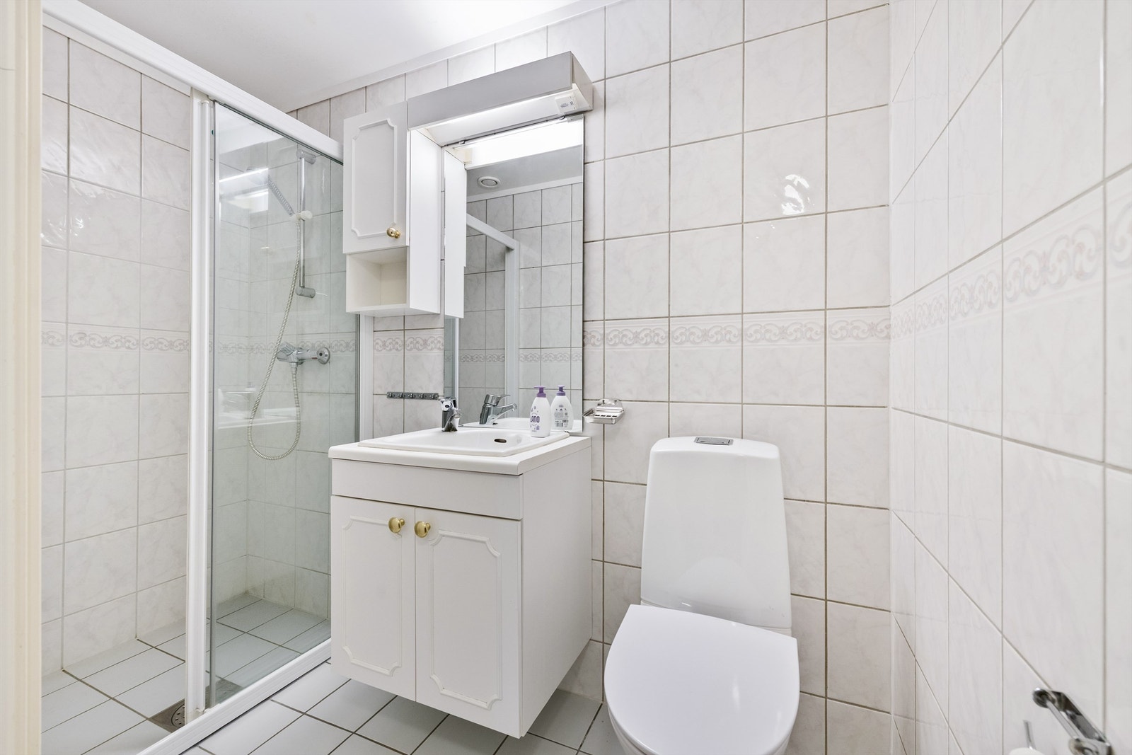 Flislagt gjestebad med adkomst fra gang. Dusjnisje, innredning med servant og speil samt wc (fra 2025) Galleribilde