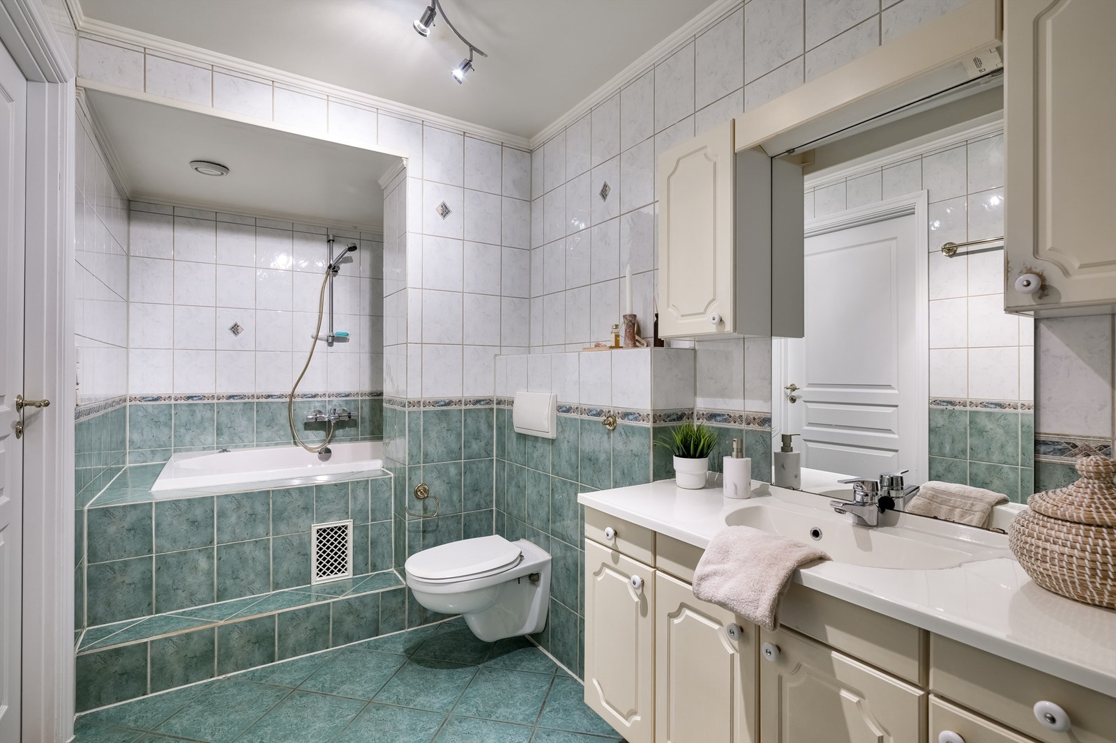 Romslig, flislagt bad med badekar, WC og servant i innredning. Galleribilde