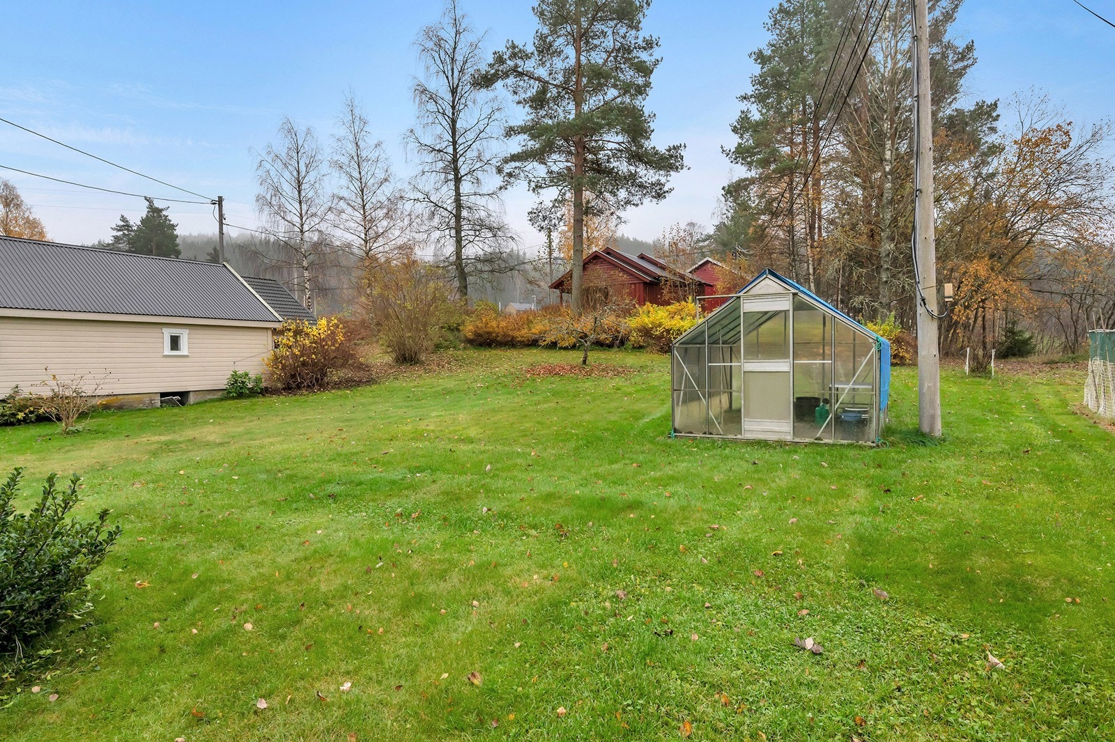 Fin hage som er opparbeidet med diverse beplanting og stor gressplen. Drivhuset medfølger. Galleribilde
