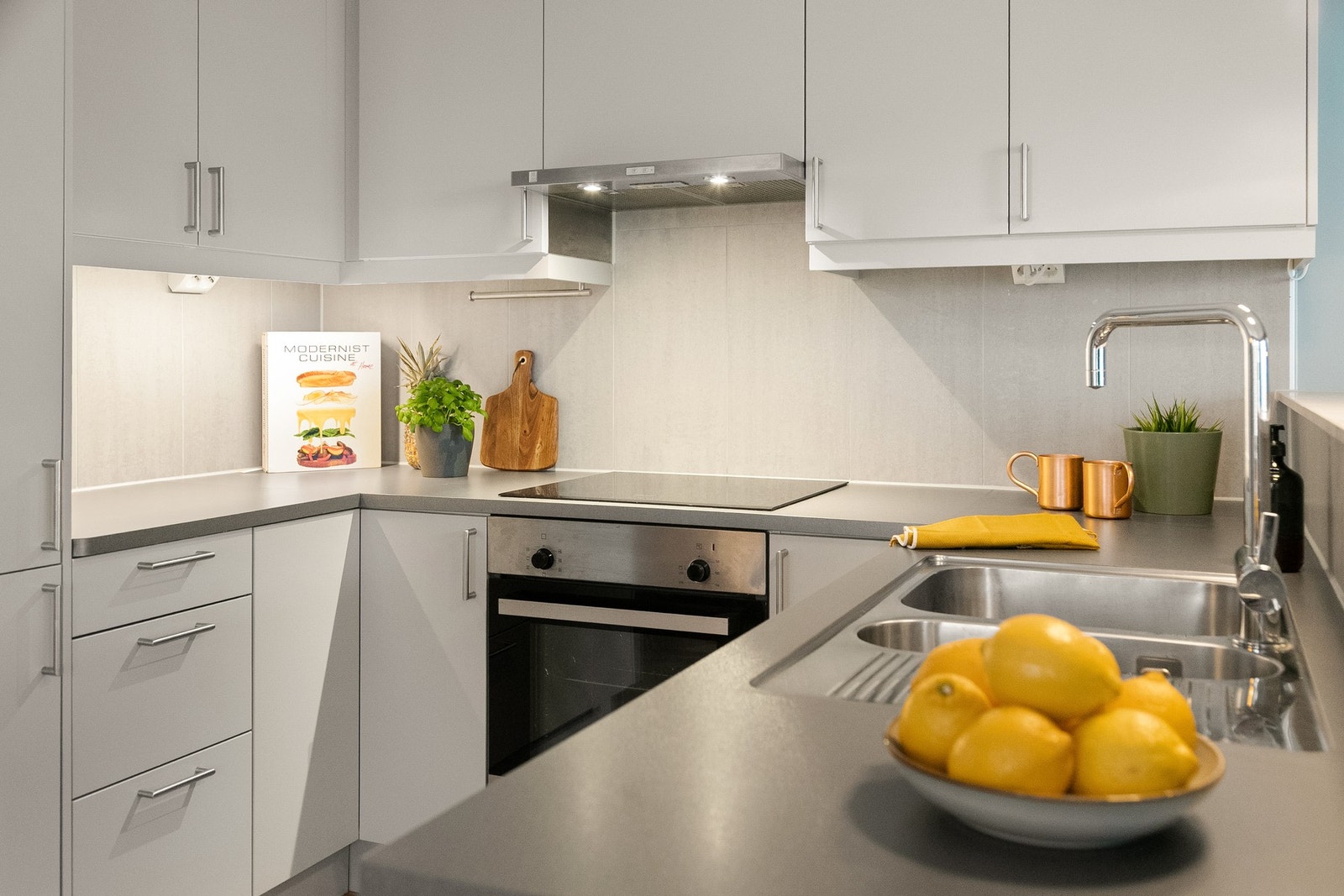 jøkkeninnredningen er utstyrt med glatte fronter, benkeplate i laminat med nedfelt kum i rustfritt stål og belysning under overskap. Galleribilde