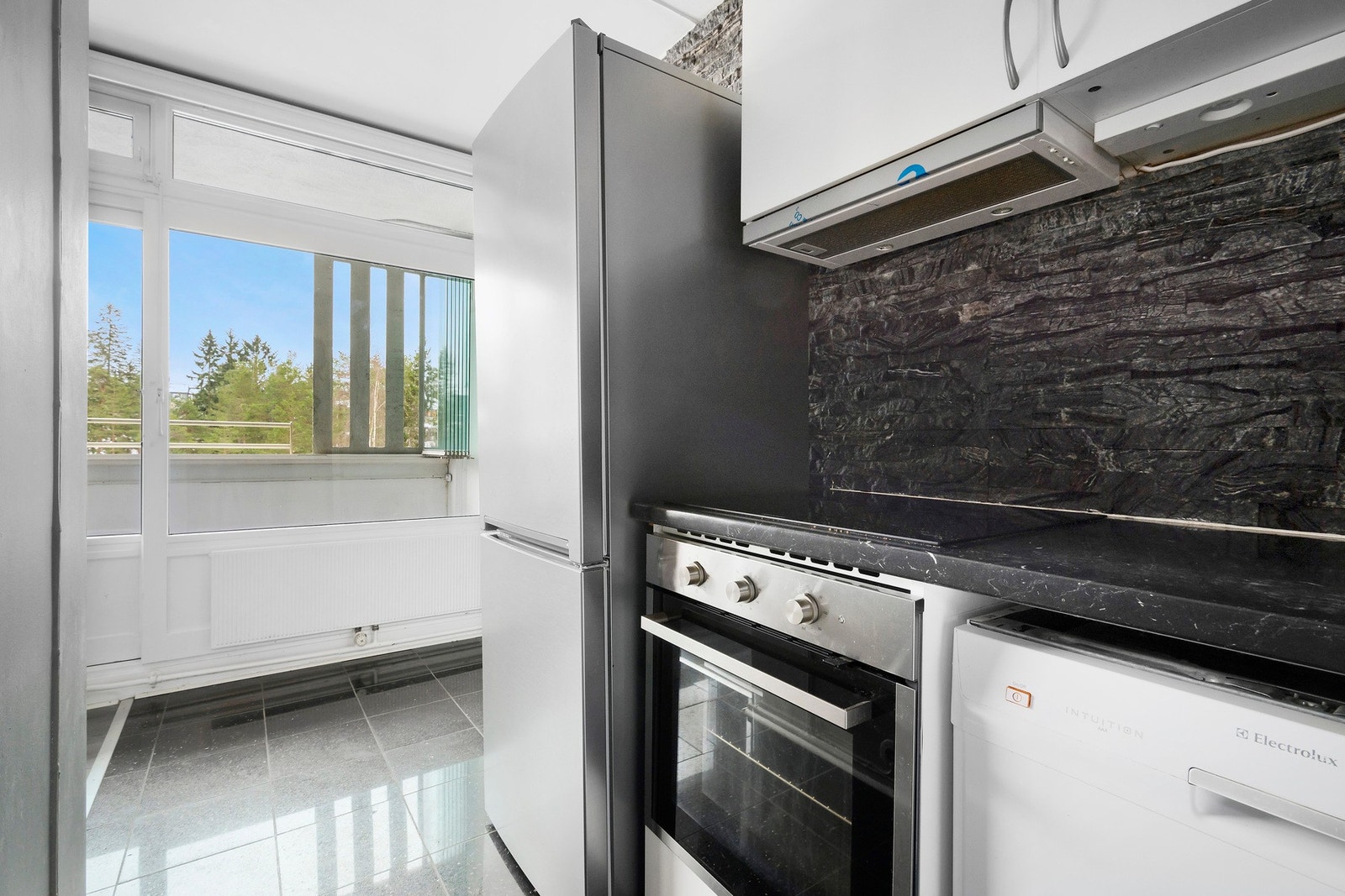 Kjøkkenet er utstyrt med frittstående hvitevarer som kjøl-/fryseskap og oppvaskmaskin, samt integrert induksjonstopp og stekeovn. Galleribilde