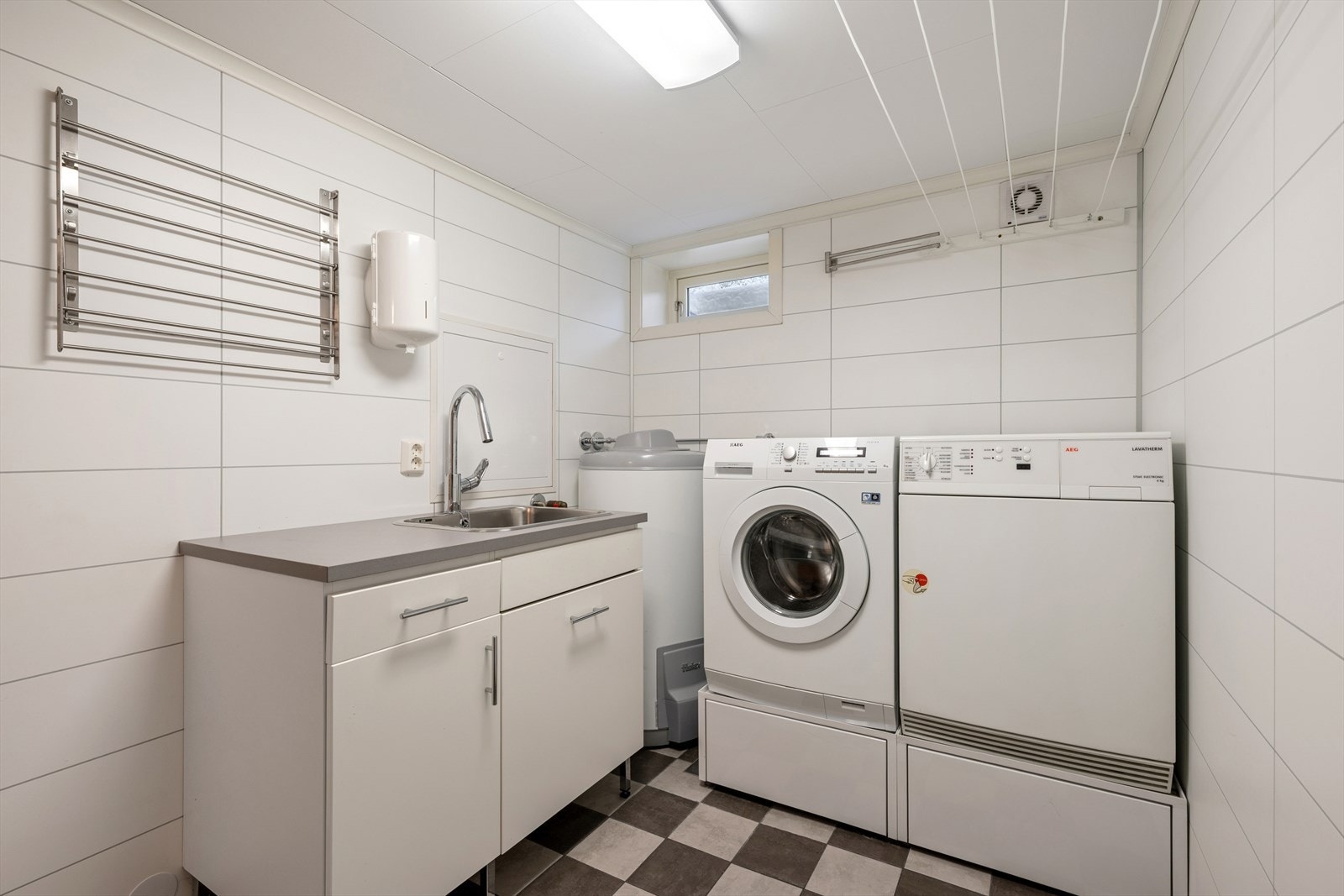 Kjellerens vaskerom er i lik stil og byr på mange praktiske løsninger. Rommet er utstyrt med varmekabler, elektrisk ventilering og utslagsvask. Galleribilde