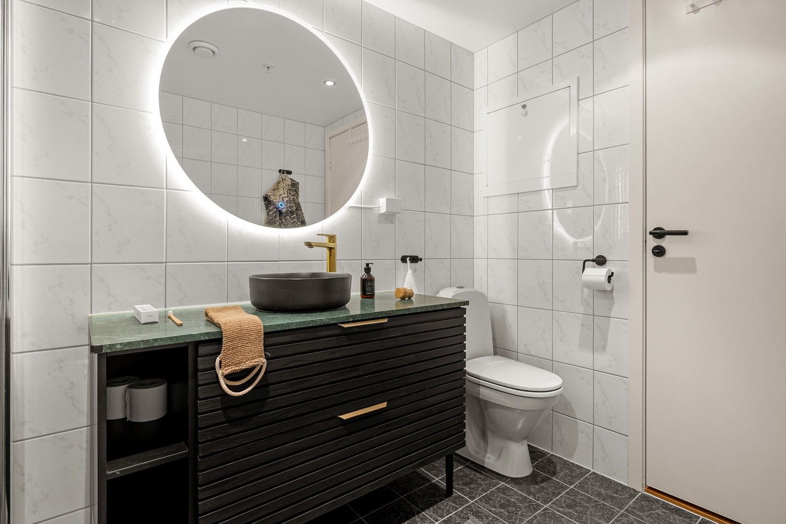 Badet er innredet med dusj med glassvegger, vegghengt toalett, servant med baderomsinnredning samt opplegg for vaskemaskin. Galleribilde