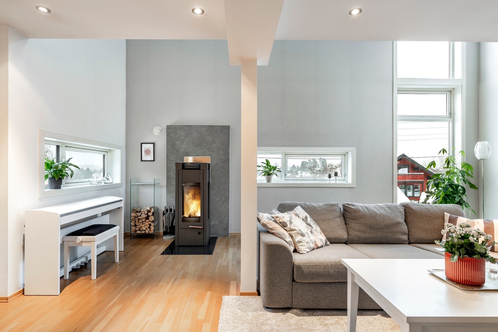 En frittstående vedovn med innsyn tilfører både ekstra varme og hygge på kjølige dager, og gjør rommet til et naturlig samlingspunkt i boligen. Galleribilde