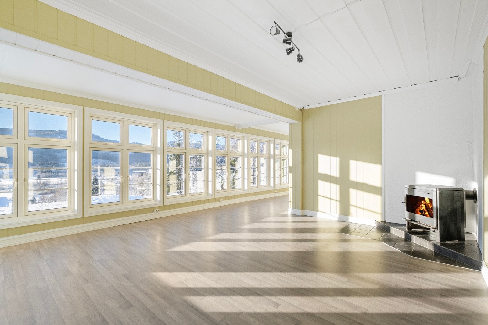 Stuen er lys og romslig med peisovn og god plass til spisebord. Galleribilde