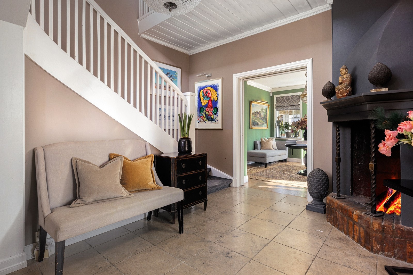 En teppebelagt trapp fører opp til andre etasje, og det er tofløyet skyvedør inn til stuen.