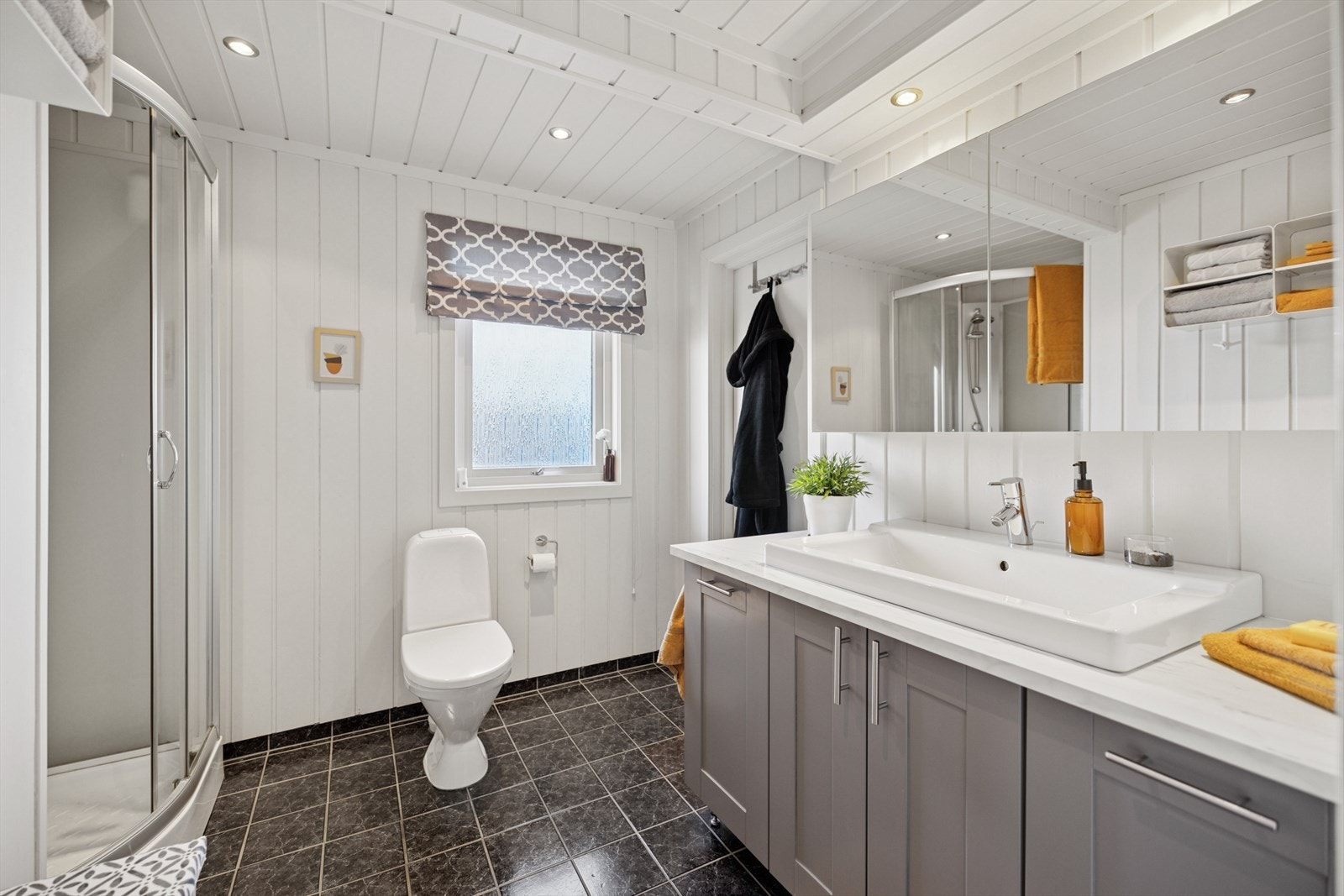 Baderommet i 1. etasje har keramiske fliser på gulvet med termostatstyrt varmekabel, samt malt panel på både vegger og i himlingen. Galleribilde