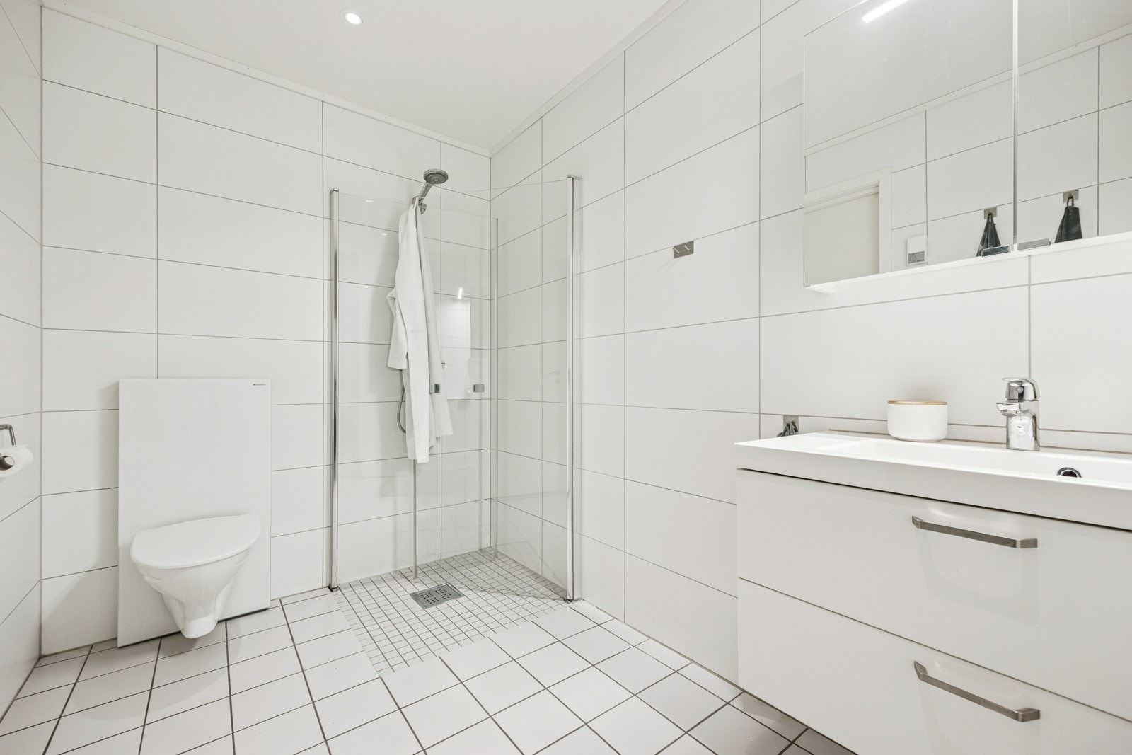 Badet fremstår med et tidløst, rent uttrykk med innfellbare glassdører i dusjsonen. Galleribilde