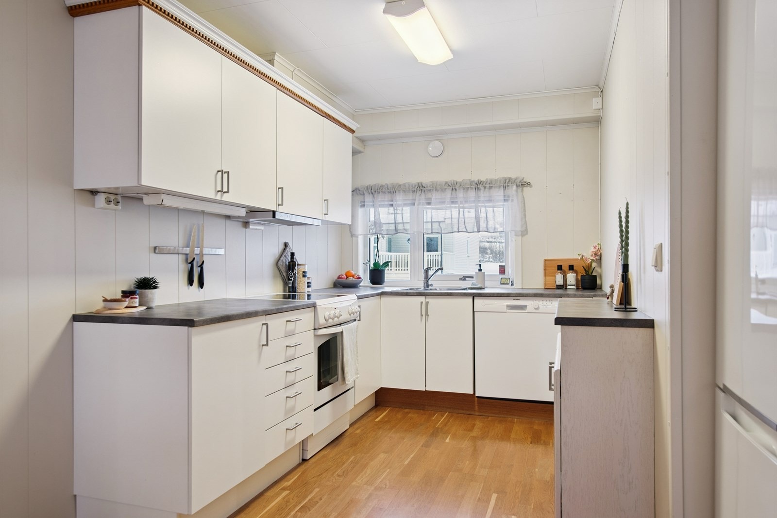 Kjøkkeninnredningen har glatte fronter, laminert benkeplate og komfyrvakt montert i 2024. Galleribilde