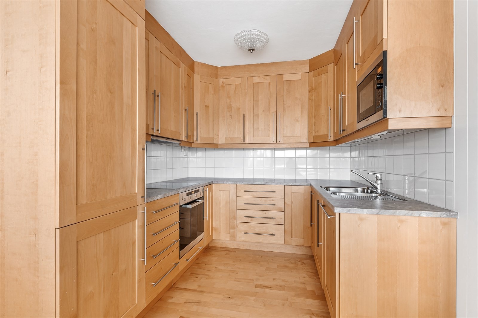 Pen kjøkkeninnredning med froner i lyst tre. Integrerte hvitevarer fra kvalitetsleverandører. Galleribilde