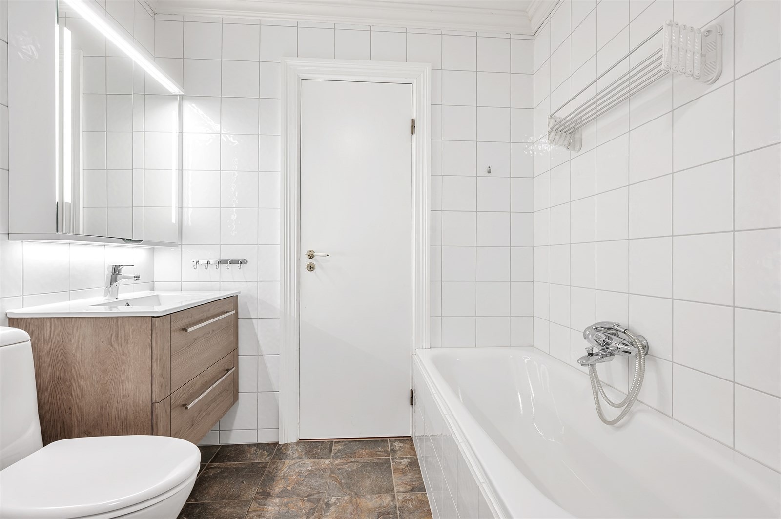 Bad/wc/vaskerom. Det er installert både badekar og dusjkabinett, klosett, baderomsinnredning, bereder og opplegg for vaskemaskin. Galleribilde