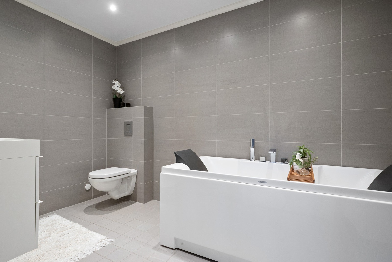 Badet er innredet med dobbel servant, veggmontert toalett og badekar. Galleribilde