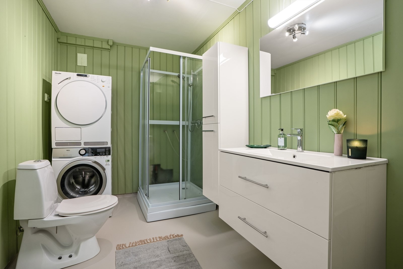 Romslig bad med plass og opplegg for vaskemaskin og tørketrommel. Det er varmekabler i gulvet Galleribilde