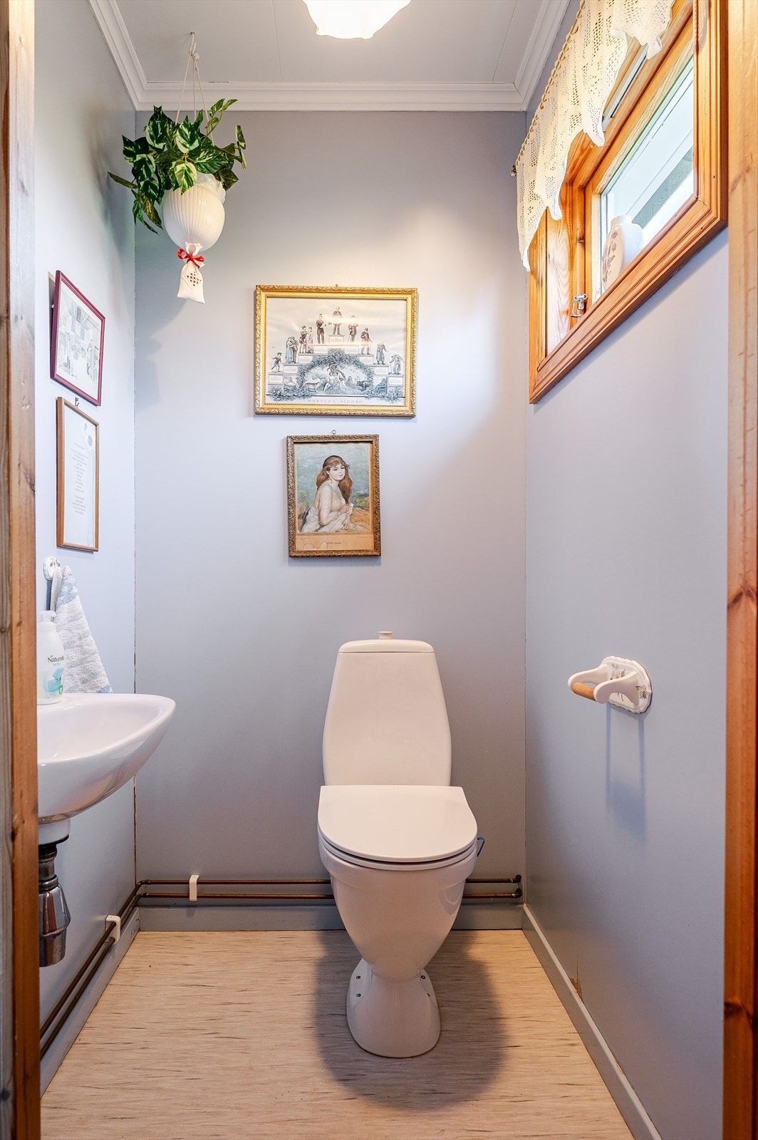 Toalettrom med vinyl på gulv med varmekabel og malte plater på veggene. Rommet er utstyrt med vegghengt servant og gulvstående toalett. Galleribilde