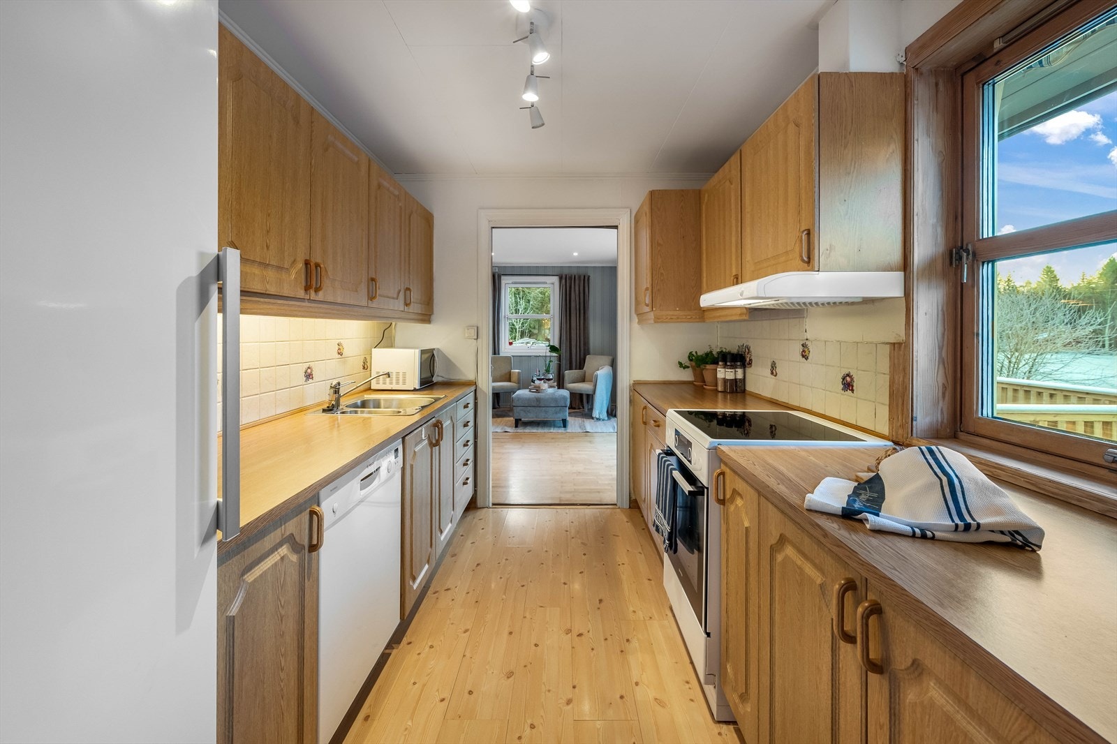 Kjøkken med profilerte fronter og laminert benkeplate med fliser på vegg over benkeplaten. Galleribilde