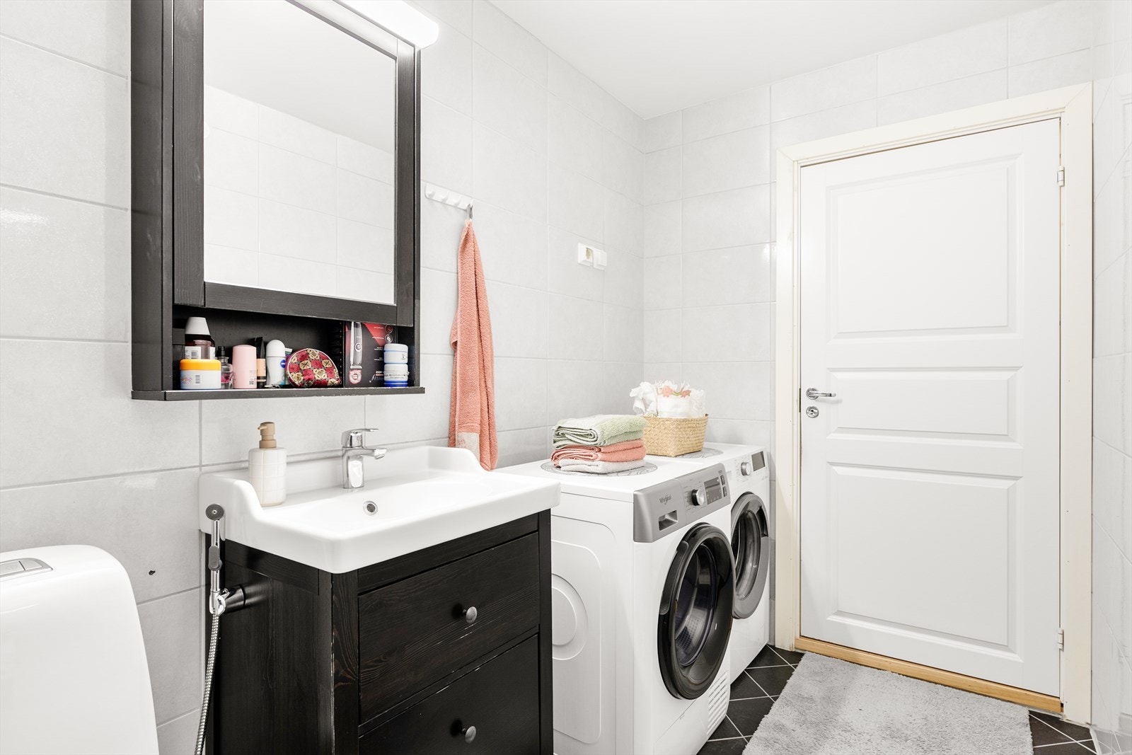 Badet inneholder servantseksjon med skuffer, gulvmontert klosett, dusj med inn-/utadslående dører og opplegg for vaskemaskin. Galleribilde