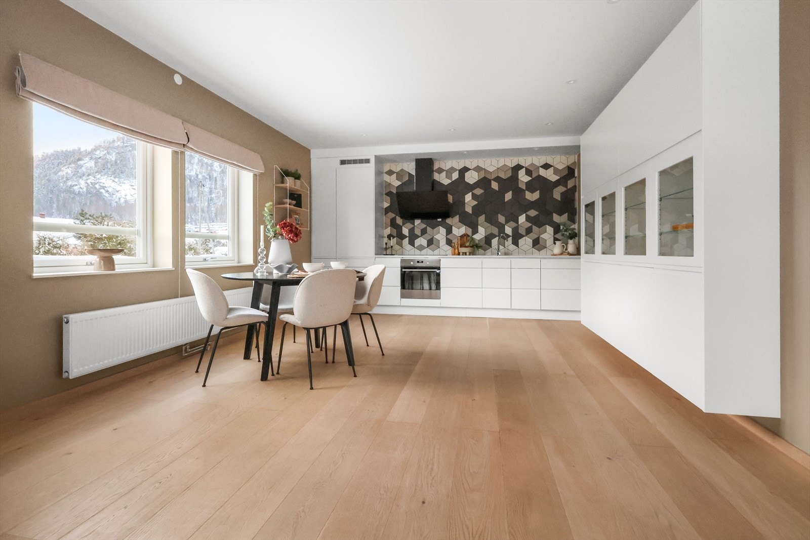 Moderne hvit kjøkkeninnredning med tilhørende stort vitrineskap. Benkeplaten er i Silestone, et dekorativt kvartskompositt. Galleribilde