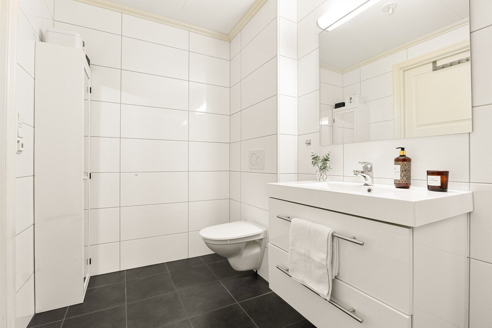 Lyst og lekkert bad med vegghengt servantinnredning, vegghengt toalett og dusjnisje med glassdører. Galleribilde