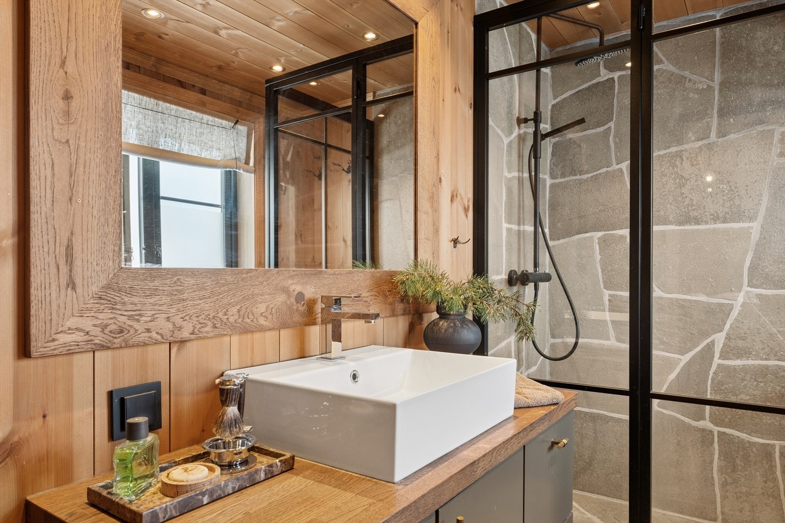 Bad i forbindelse med hovedsoverom. Delikat bruddskifer i dusjsonen og på gulv med gulvvarme, trepanel i himlingen med innfelte downlights. Galleribilde