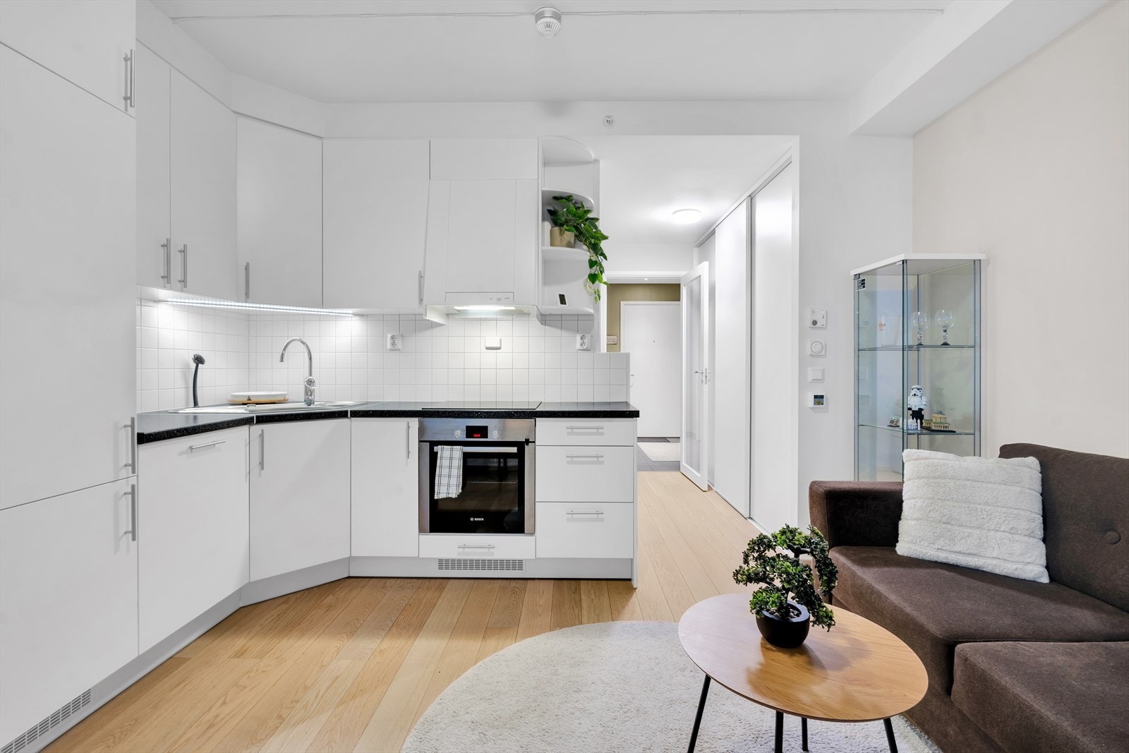 Lyst og pent kjøkken med integrerte hvitevarer, i åpen løsning til stue. Galleribilde