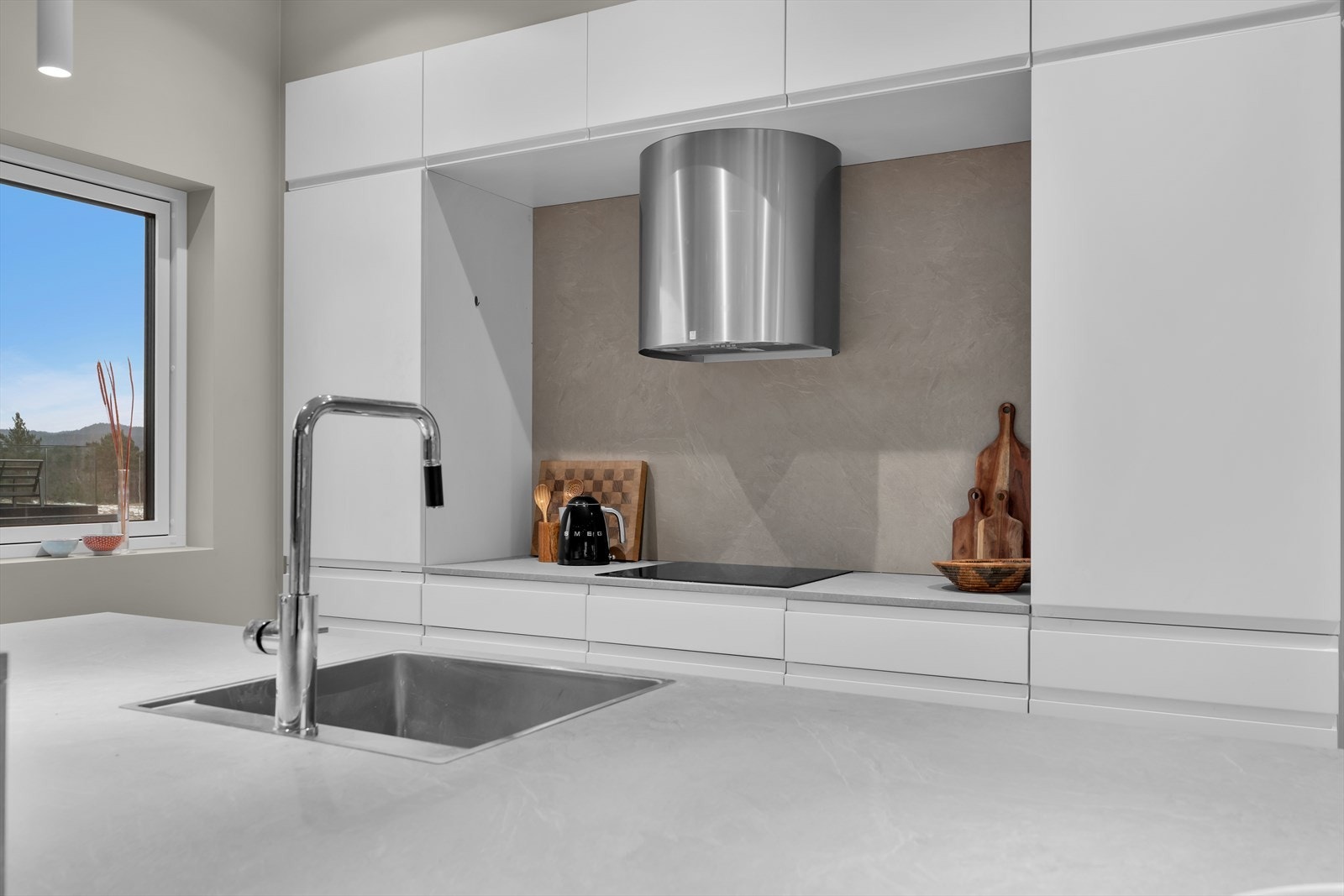 Kjøkkenet er utstyrt med integrerte hvitevarer som gir et rent og helhetlig uttrykk, samt en elegant Røroshetta ventilator over steketoppen som tilfører et eksklusivt preg. Galleribilde