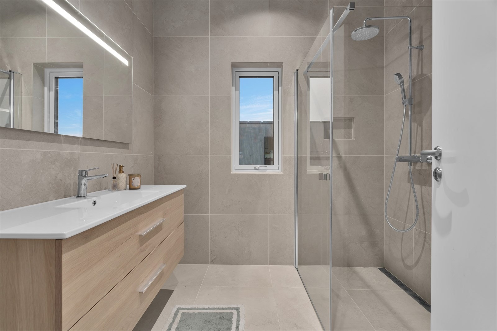 Dette romslige baderommet er flislagt på både gulv og vegger, med varme i gulvet for ekstra komfort. Galleribilde