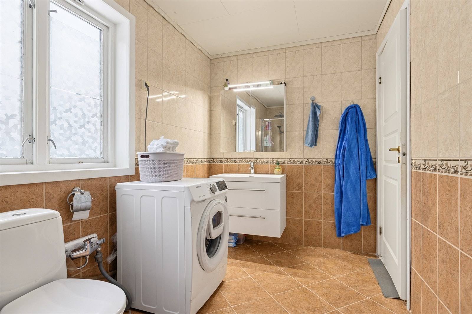 På badet er det dusjnisje med glassdører, toalett og baderomsinnredning. Opplegg for vaskemaskin. Galleribilde