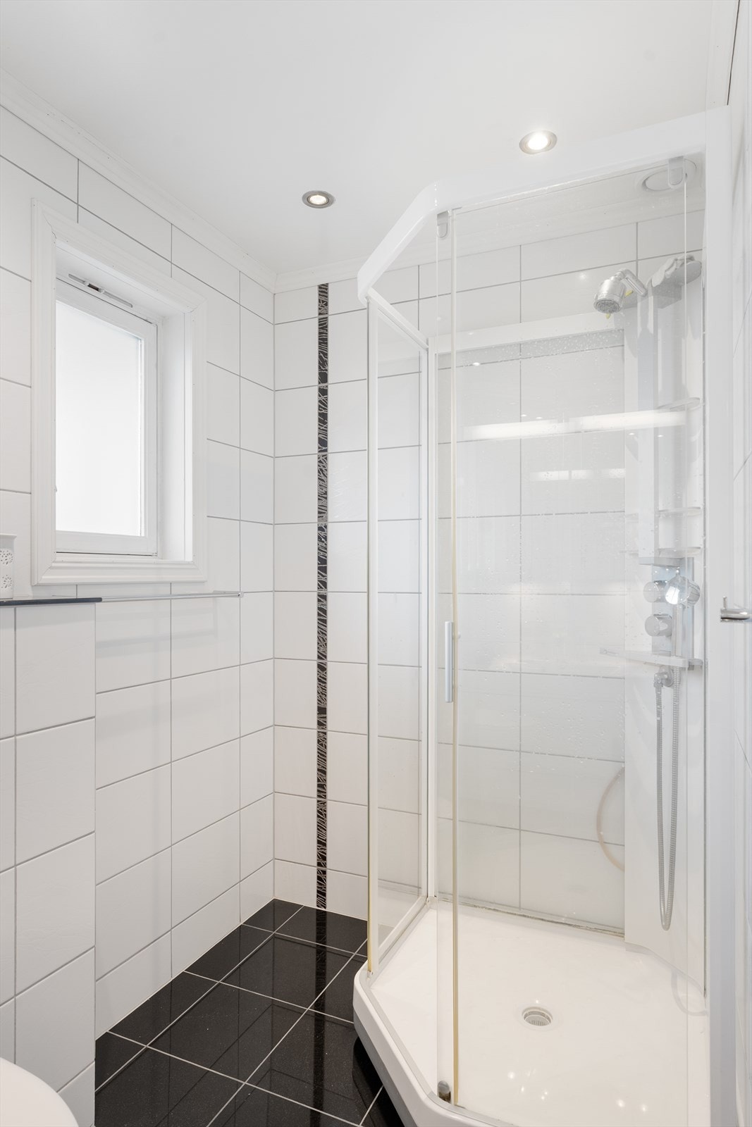 Badet er innredet med hvit baderomsinnredning, dusjkabinett og vegghengt toalett Galleribilde