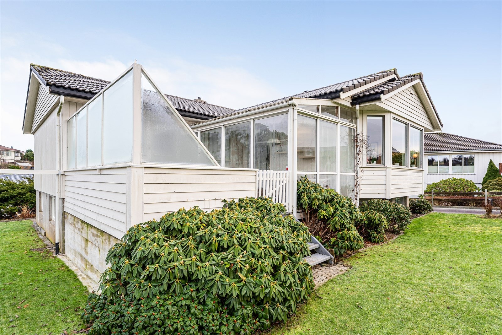 Boligen har en usjenert terrasse med tilhørende hagestue Galleribilde