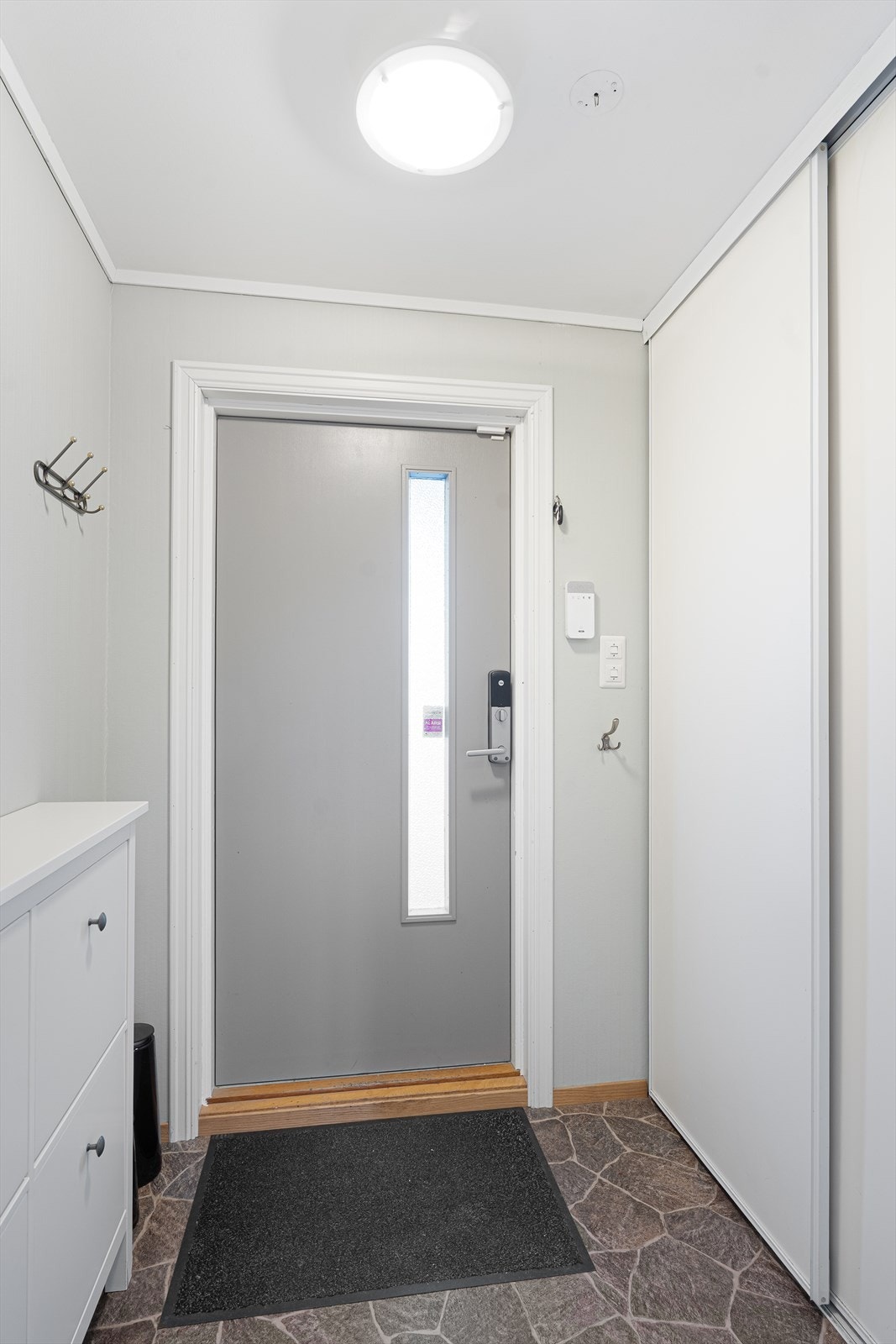 Et lyst vindgang ønsker deg velkommen inn - her er det godt med oppbevaringsplass i praktisk skyvedørsgarderobe Galleribilde