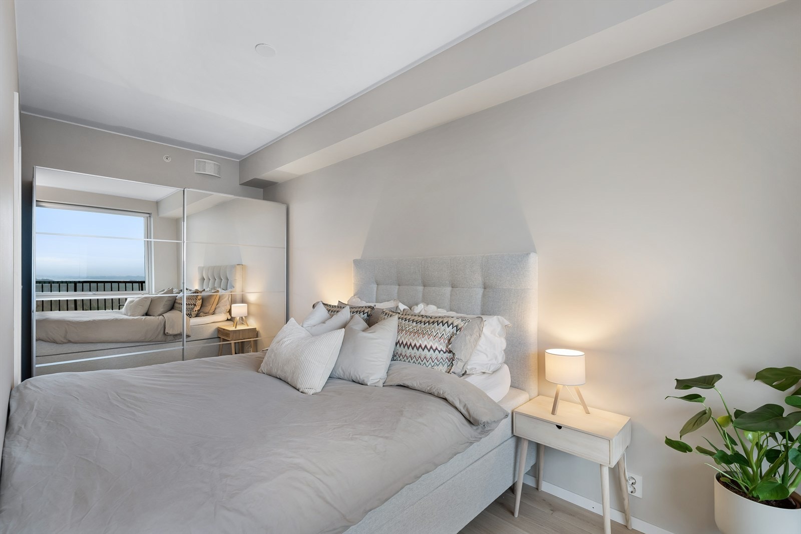 Langs veggen mot kjøkkenet er det en skyvedørsgarderove med speilfronter som rommer det meste. Galleribilde