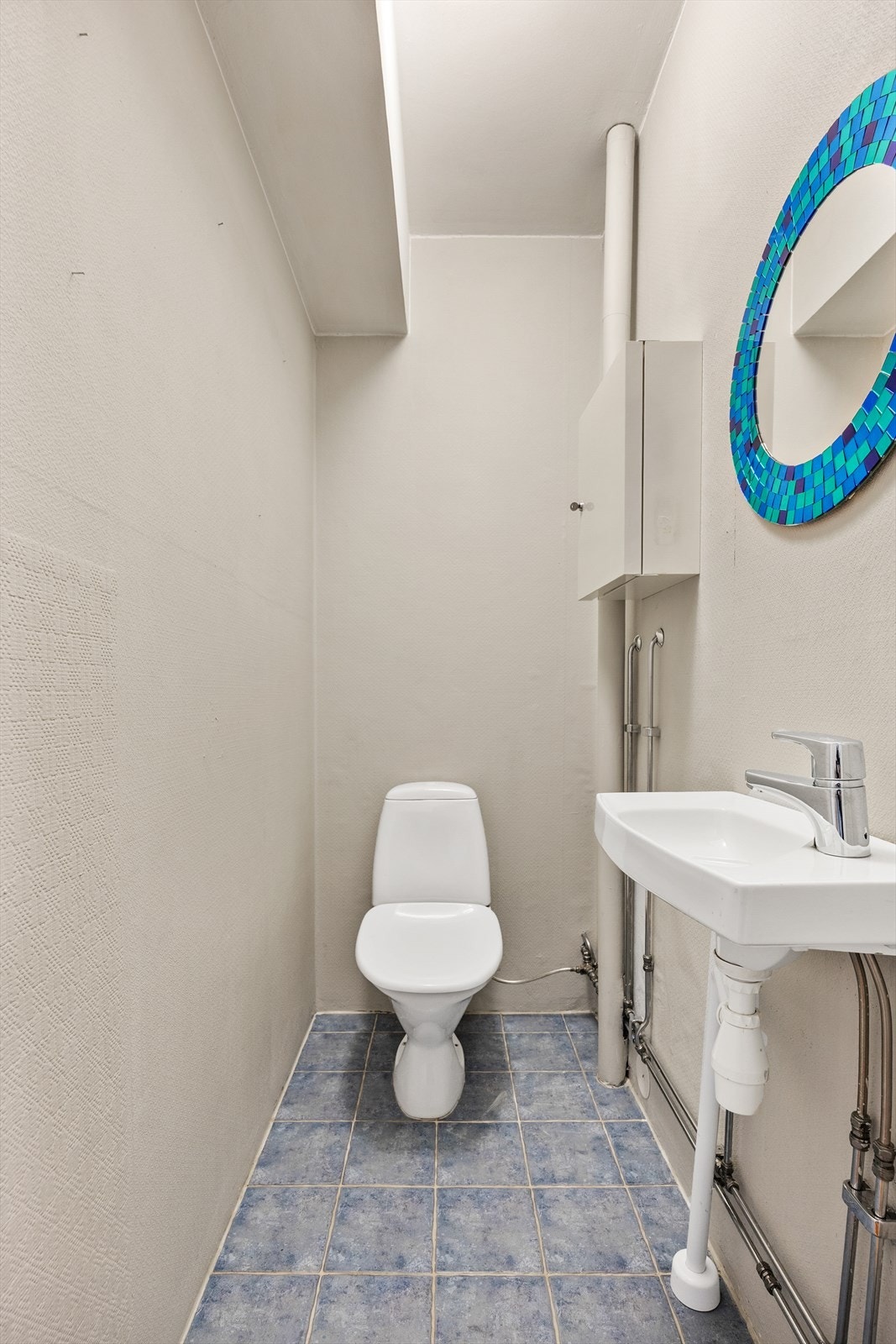 Praktisk separat toalettrom med fliser på gulv, servant og klosett. Galleribilde