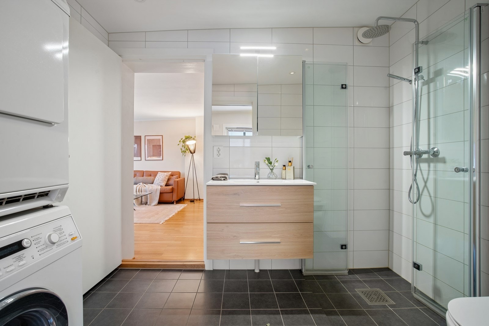 Badet byr på et praktisk dusjhjørne med innfellbare dører og har plass til oppvaskmaskin og tørketrommel Galleribilde