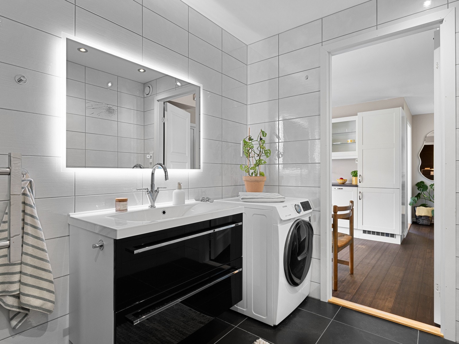 Badet er innredet med servant på skuffeseksjon og speil. Videre er badet utstyrt med toalett, dusjhjørne og opplegg til vaskemaskin. Galleribilde