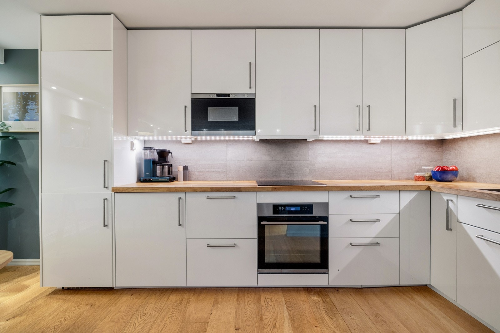 Kjøkkenet fremstår som moderne og gjennomført med høyglans hvit kjøkkeninnredning og rustfrie håndtak som gir et stilrent og tidløst uttrykk. Galleribilde